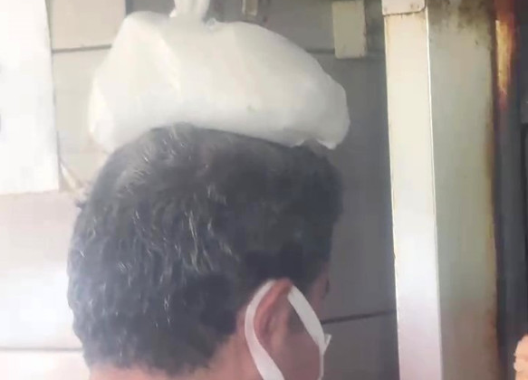 Dönerci ustası kavurucu sıcakta, ateş karşısında kafasına buz torbası koyarak serinlemeye çalıştı